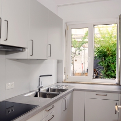 Eine weiß möblierte Küche mit Blick aus dem Fenster - ins Grüne.
